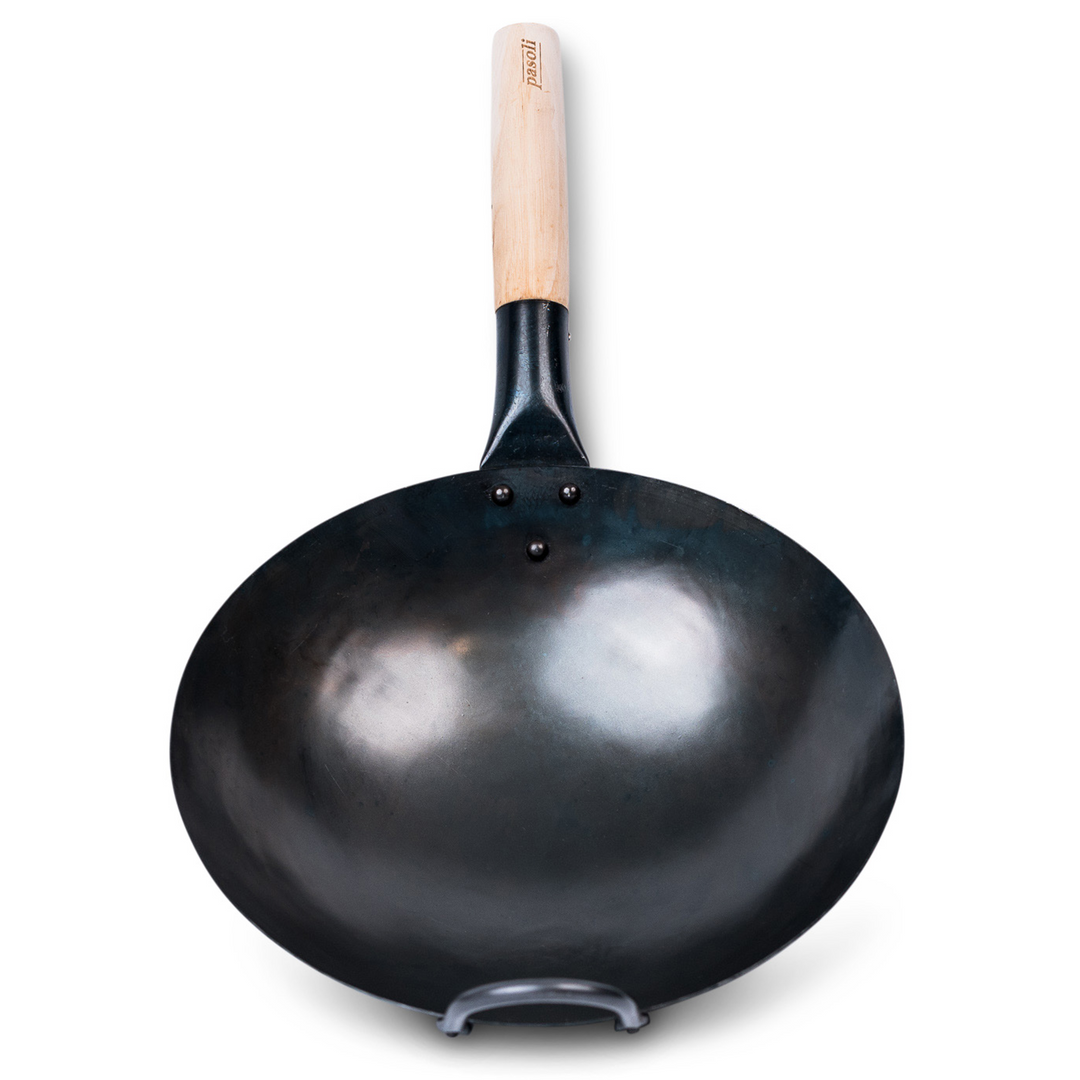 Vista superior del wok de pasoli tradicionalmente martillado a mano y presazonado con fondo redondo.