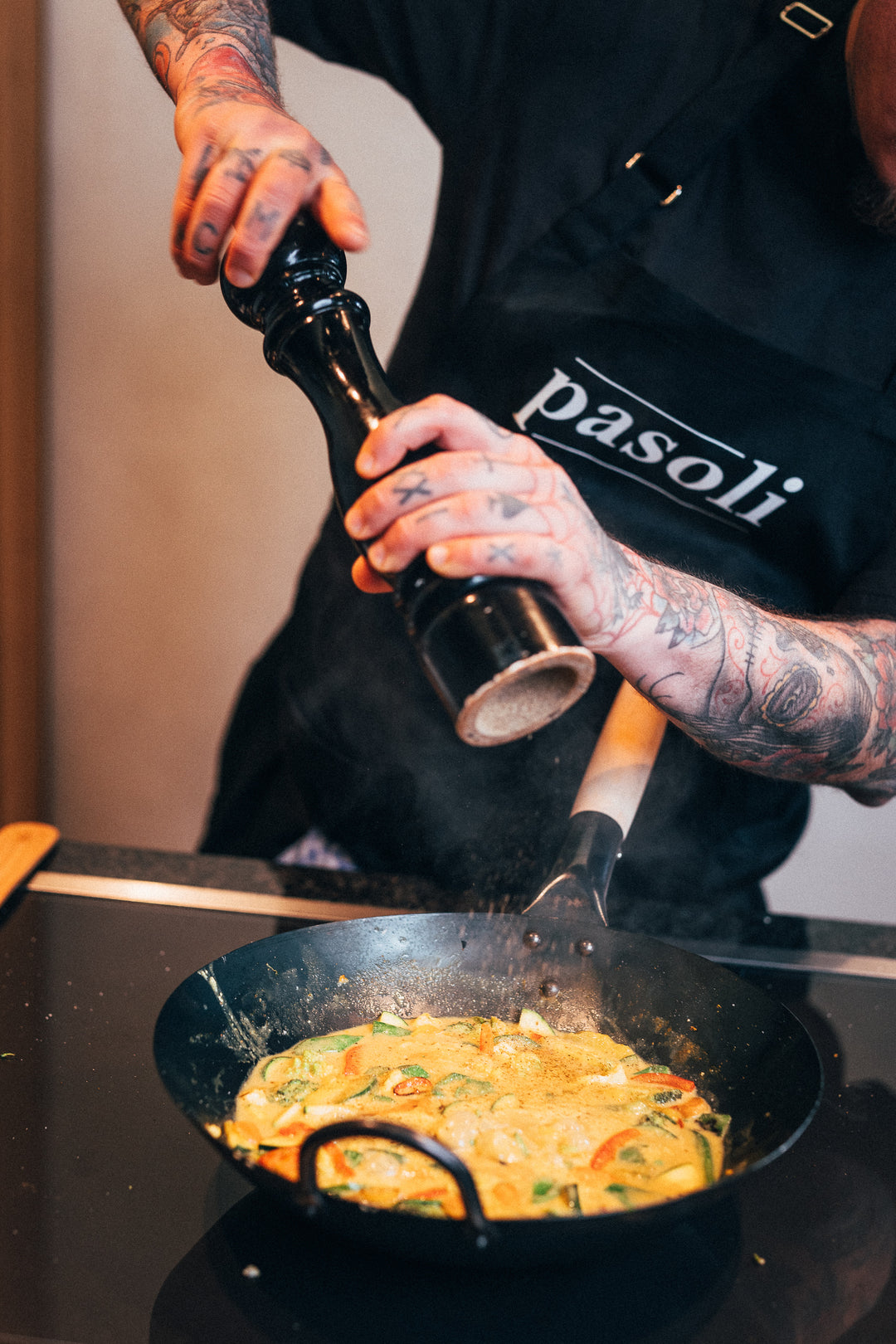 Nuestro chef profesional Mane utiliza un gran molinillo de pimienta para sazonar su deliciosa sartén de verduras en nuestro wok de pasoli.
