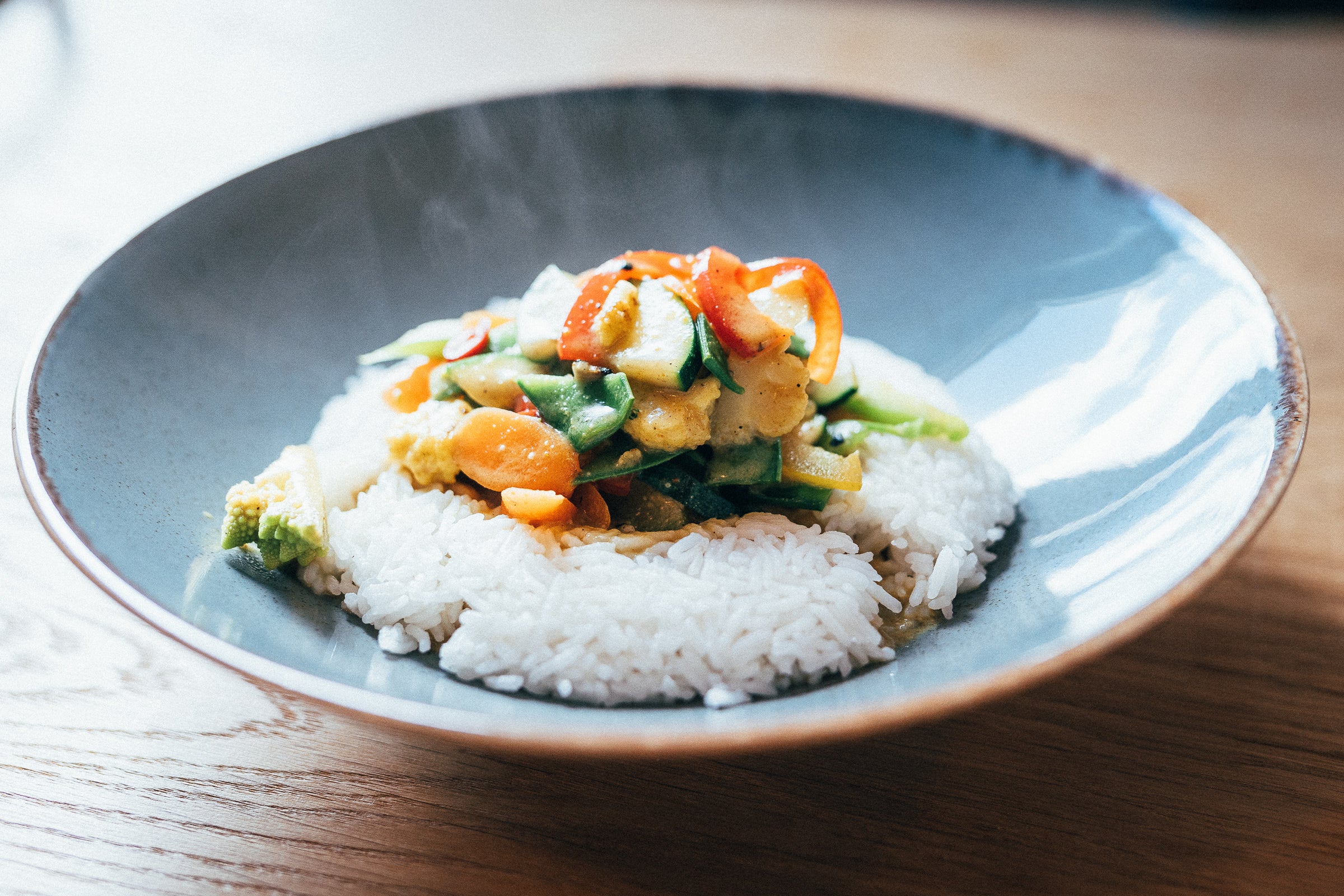 Deliciosas verduras sobre arroz servidas en un hermoso plato azul.